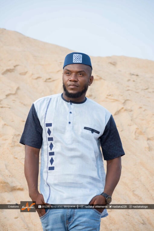 Homme portant une chemise brodée Nadiaka bleu au bord de la plage