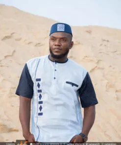 Homme portant une chemise brodée Nadiaka bleu au bord de la plage