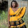 Robe batik couleur or et noire, évasée à double ovale superposées, manches asymétriques à volants, avec ceinture brodée.
