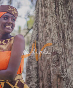 Robe longue brodée, en pagne tissé orange à brillantine or, Avec ceinture large brodée. Foulard et chapeau brodé assortis.