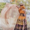 Robe longue, haut drapé, en tissu batik couleur moutarde et marron. Avec ceinture large brodée et tulles traîne brillant marron. Foulard et chapeau brodé assortis.