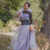 Robe longue, en pagne tissé couleur argentée, à brillantine argent, mix tulles brillant argent et dentelles noires. Avec ceinture large brodée et froufrous. Foulard et chapeau brodé assortis.