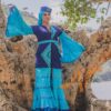 Robe longue volantée, brodée, en pagne tissé à brillantine, mix tissu batik couleur bleue turquoise et bleu. Avec ceinture large asymétrique brodée. Foulard et chapeau brodé assortis.