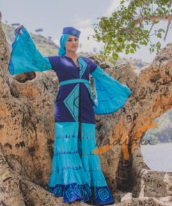 Robe longue volantée, brodée, en pagne tissé à brillantine, mix tissu batik couleur bleue turquoise et bleu. Avec ceinture large asymétrique brodée. Foulard et chapeau brodé assortis.