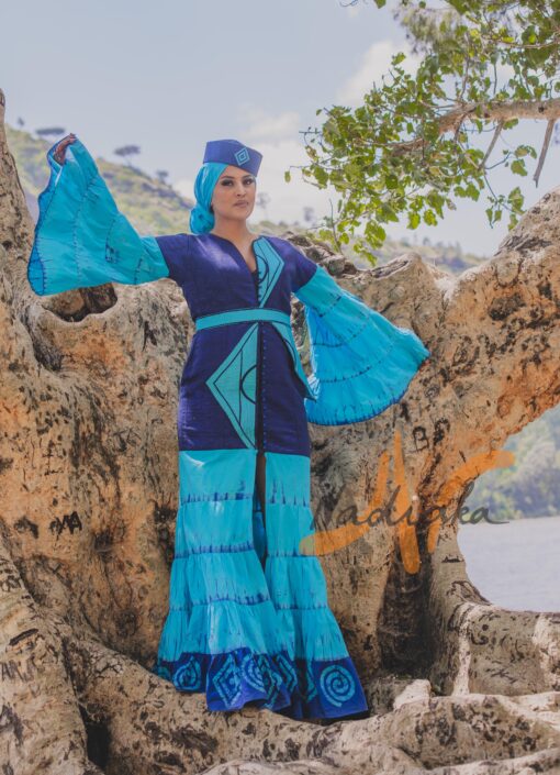 Robe longue volantée, brodée, en pagne tissé à brillantine, mix tissu batik couleur bleue turquoise et bleu. Avec ceinture large asymétrique brodée. Foulard et chapeau brodé assortis.