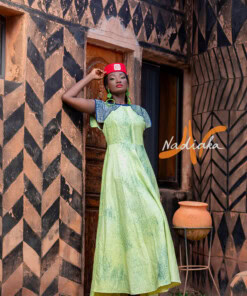Robe longue de couleur verte, brodée en teinture à jets , ovale de la taille jusqu'au bas assortie d'un chapeau Apéto rouge à motif blanc