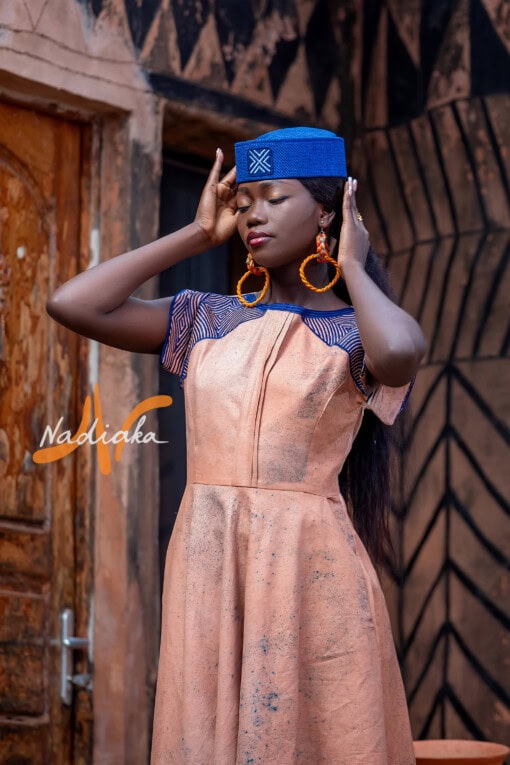 Robe longue ovale en teinture à jets marron assortie avec un chapeau apéto bleu et des boucles d'oreilles en pailles