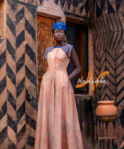 Robe longue ovale en teinture à jets nude assortie avec un chapeau apéto bleu et des boucles d'oreilles en pailles