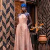 Robe longue ovale en teinture à jets nude assortie avec un chapeau apéto bleu et des boucles d'oreilles en pailles