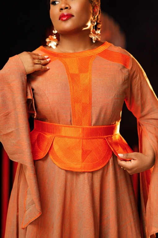 Longue robe de soirée en col V brodée munie d'une ceinture brodée jaune moutarde. Les manches sont longues et asymétriques
