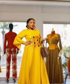 Longue robe brodé de couleur jaune moutarde avec manches 3/4 en tissu coton woodin avec des broderies à l'avant. La robe est agrémentée de fentes en bas sur chaque coté de la robe