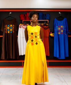 Longue robe brodé de couleur jaune moutarde sans manches en tissu coton woodin avec des broderies à l'avant. La robe est agrémentée de fentes en bas sur chaque coté.